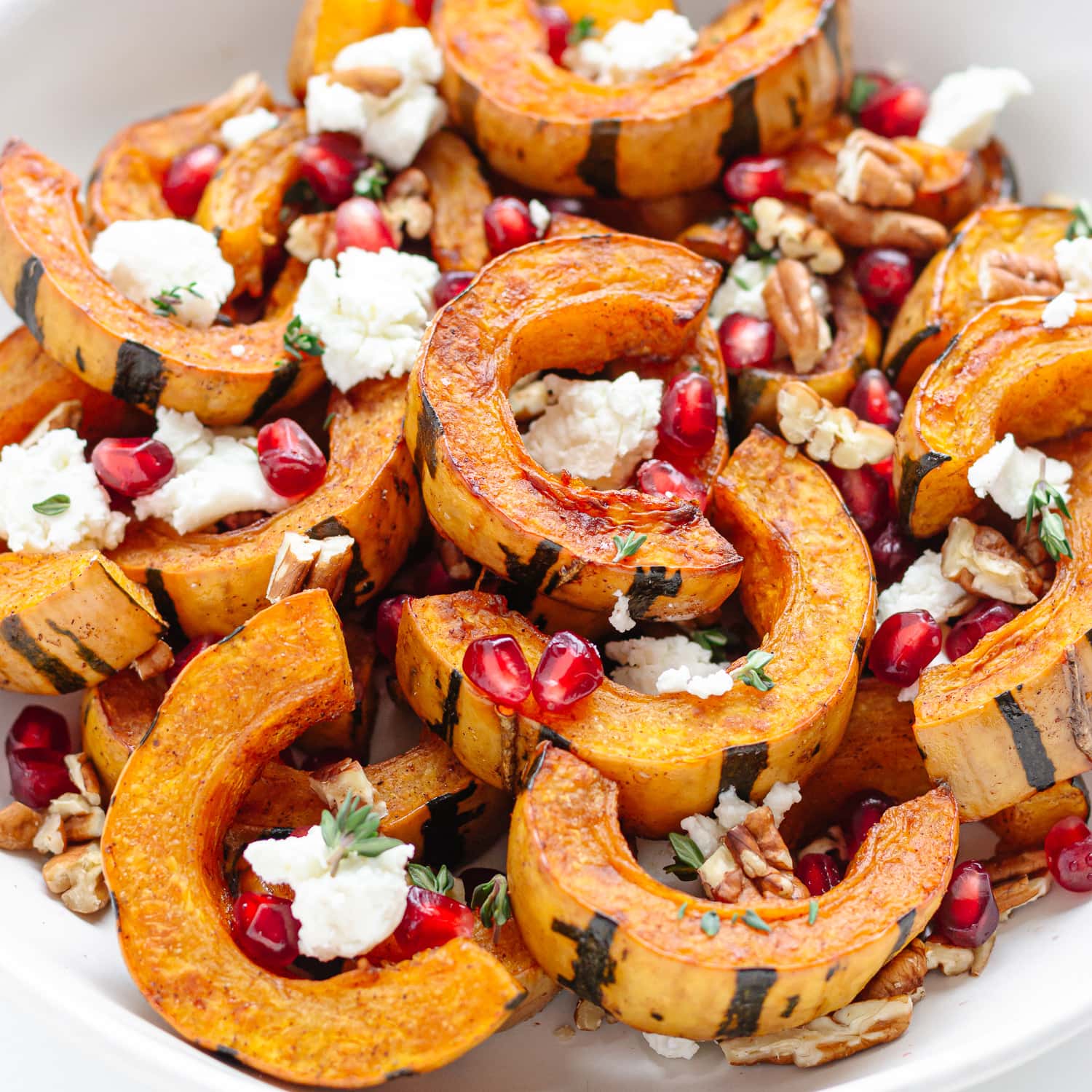 Baked delicata squash slices garnished with goat cheese, pomegranate, pecans and thyme.