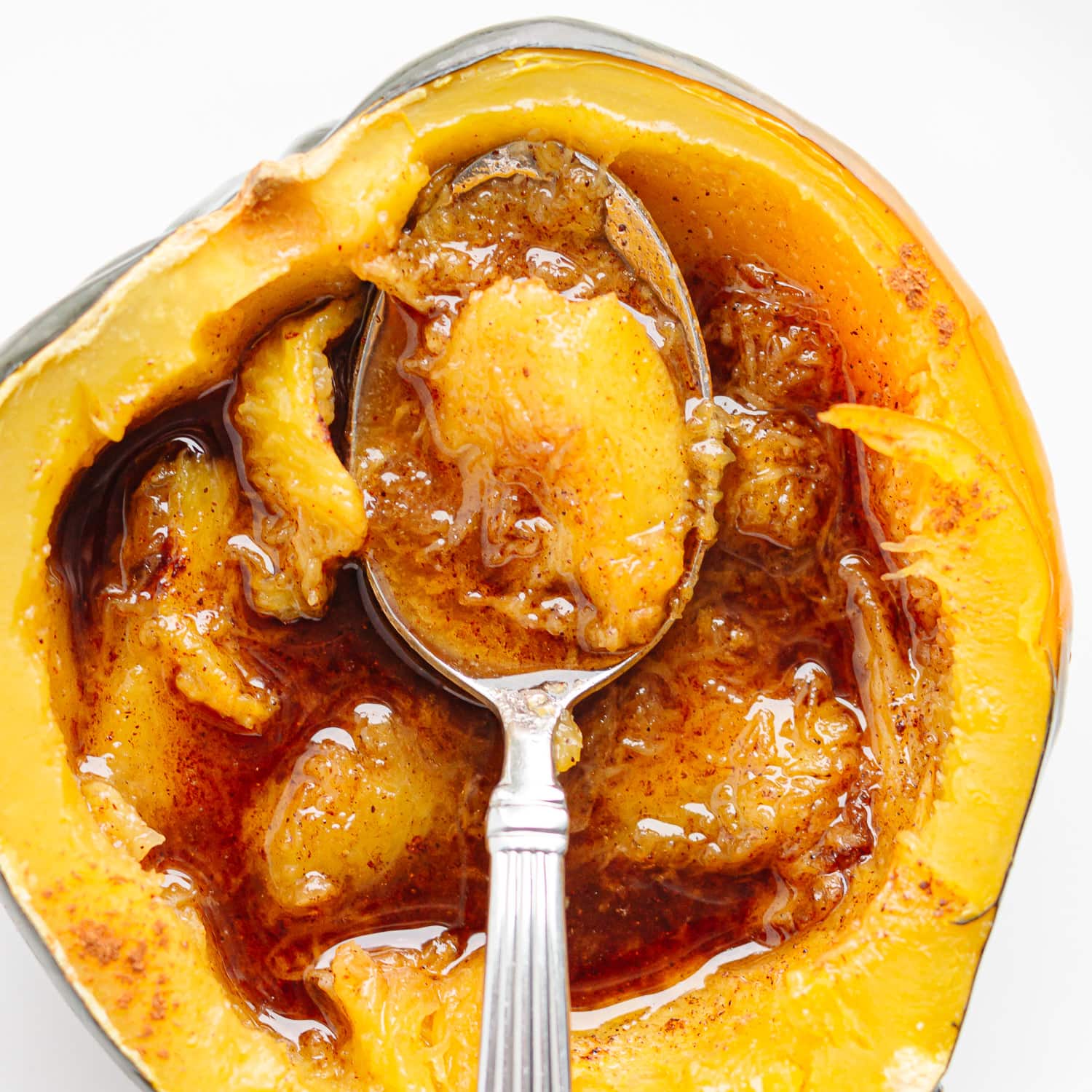 Closeup of half an acorn squash with butter and brown sugar and a spoon sitting on top.