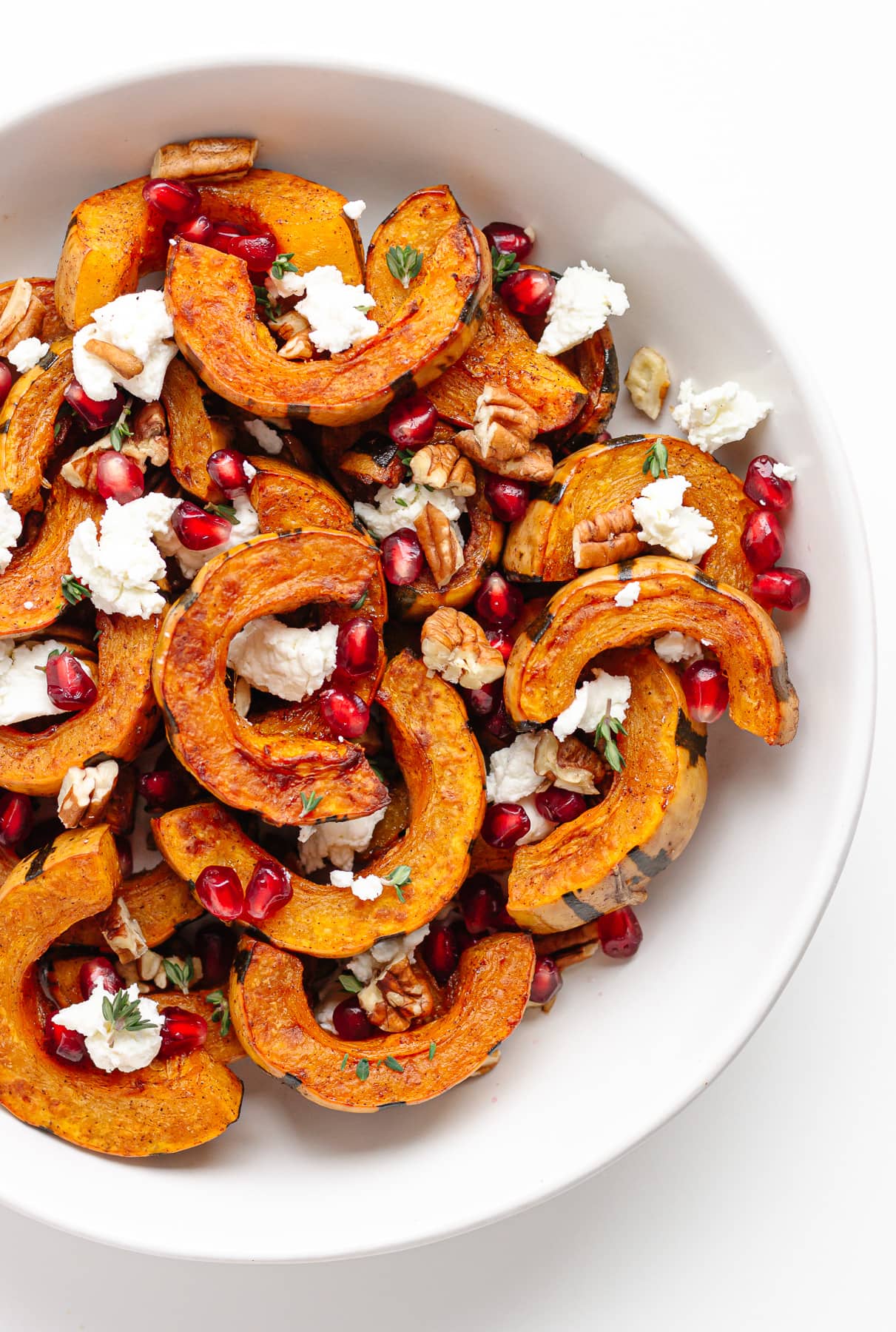 Roasted delicata squash slices garnished with goat cheese, pomegranate arils, chopped pecans and thyme.