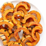 Roasted delicata squash slices on a white serving plate.