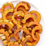 Roasted delicata squash slices on a white serving plate.