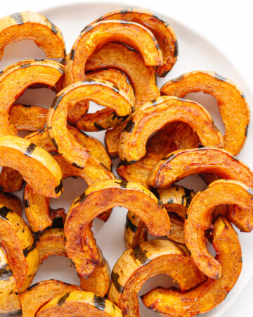Roasted delicata squash slices on a white serving plate.