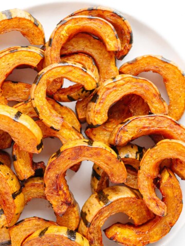 Roasted delicata squash slices on a white serving plate.