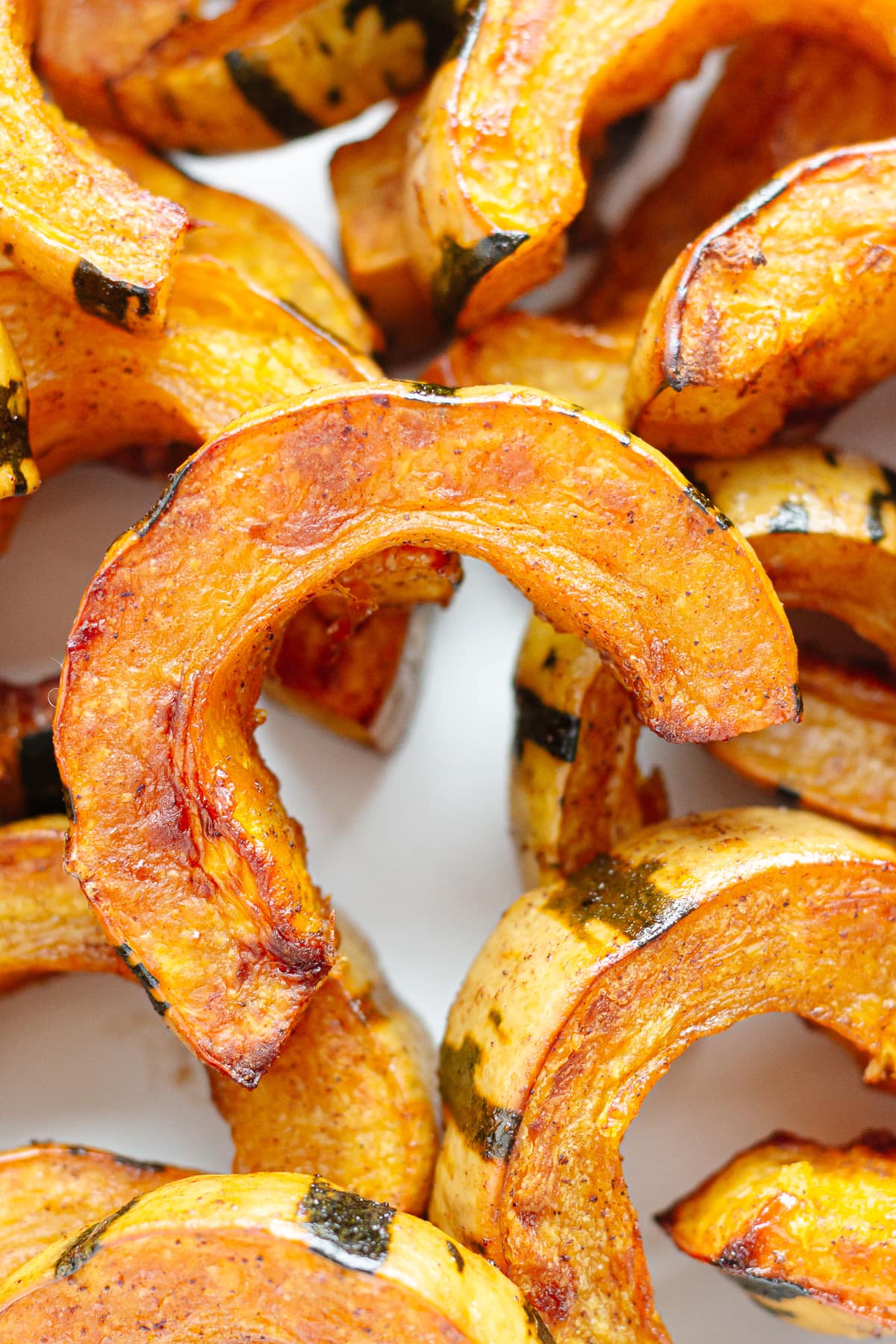 Closeup of roasted delicata squash half moon slices.