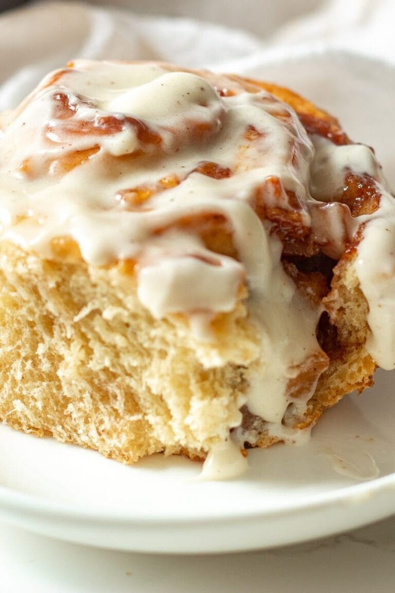 A single apple pie cinnamon roll on a white plate.