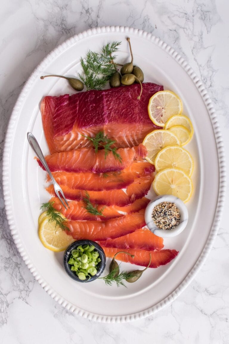 Beet cured salmon on a white platter with garnishes.