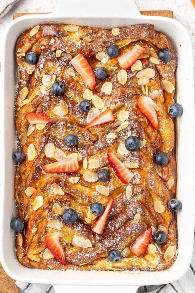 Brioche french toast casserole garnished with fresh strawberries and blueberries.