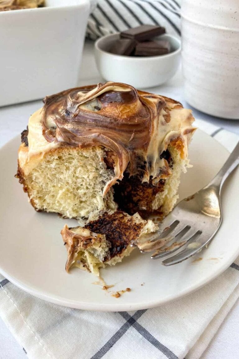 Chocolate dulce de leche roll on a white plate with fork.