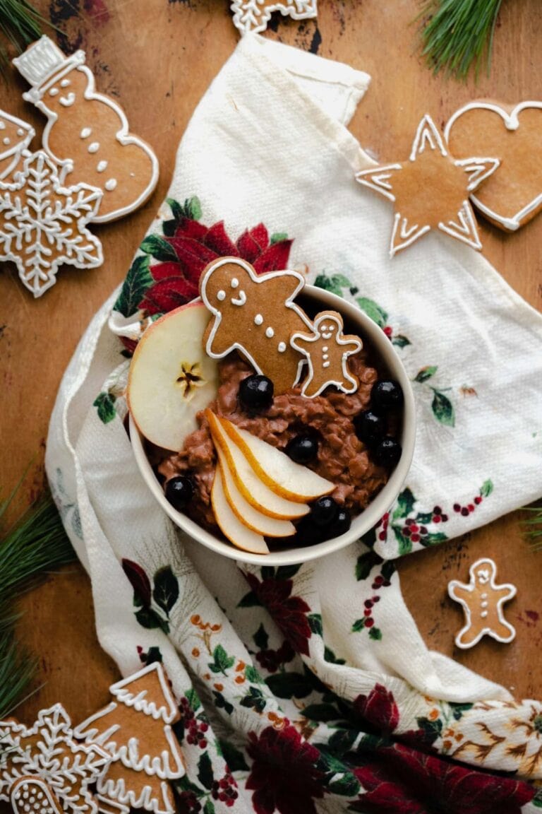 Chocolate gingerbread oatmeal garnished with a gingerbread man, pear slices and cherries.