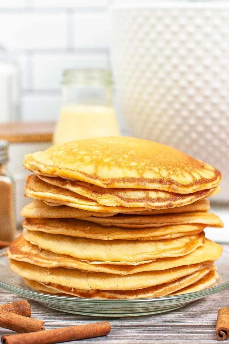Stack of eggnog pancakes on a clear glass plate.
