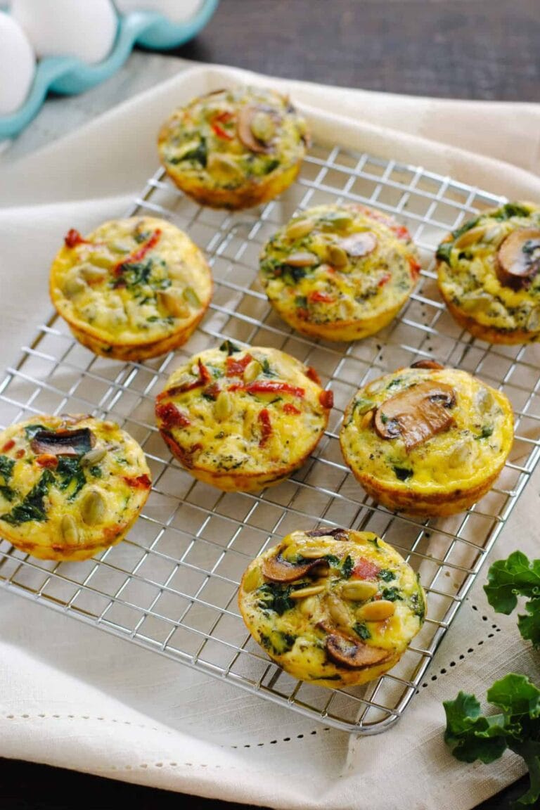 Breakfast egg muffins with different toppings sitting on a wire cooling rack.