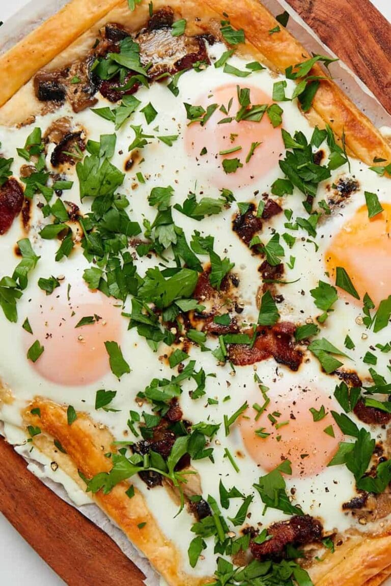 Puff pastry breakfast tart with eggs and bacon garnished with chopped parsley.