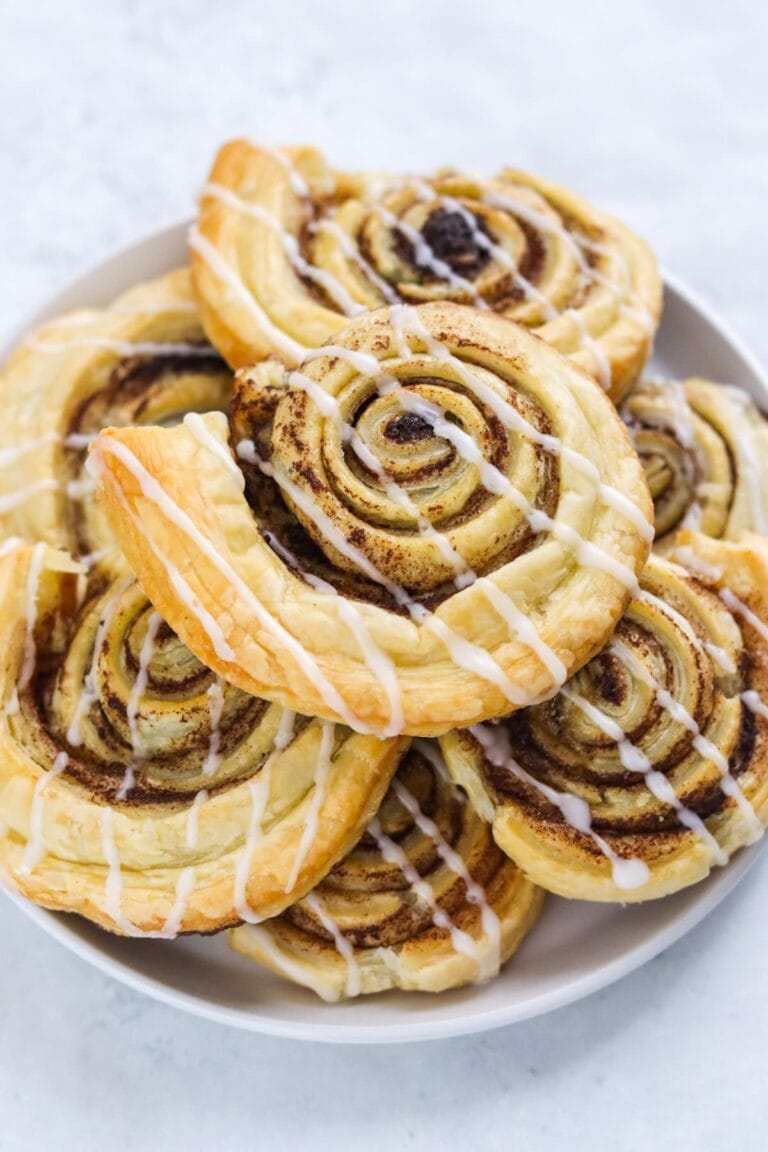 Pile of puff pastry cinnamon swirls on a white plate.