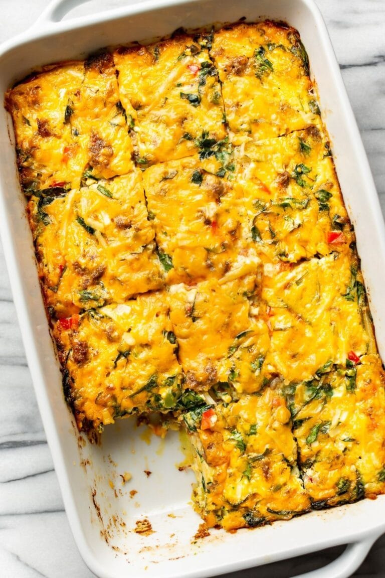 Breakfast casserole in a white casserole dish with one slice missing.