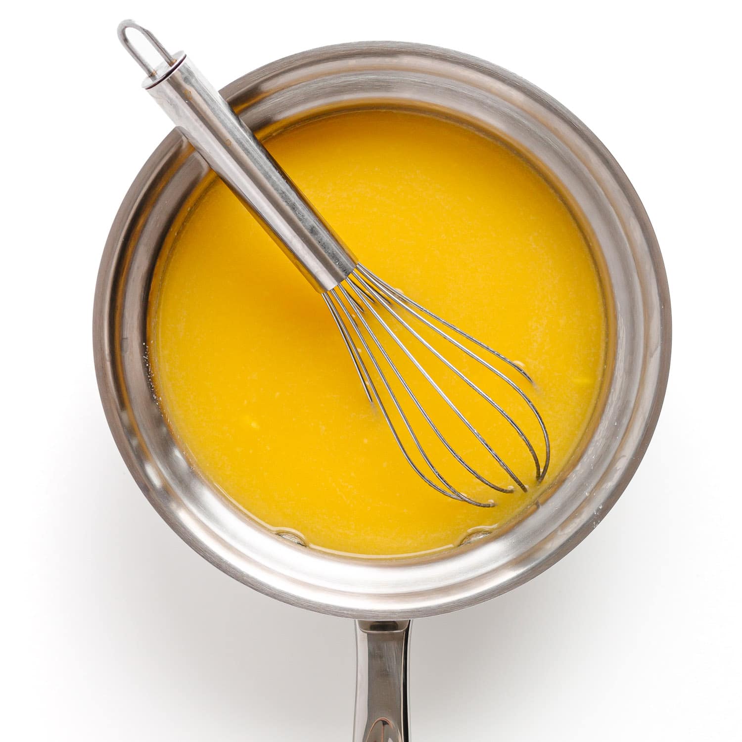 Mango puree, water, and honey in a saucepan with a whisk.