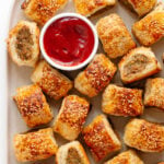 Closeup of chicken sausage rolls on a platter with small bowl of ketchup.