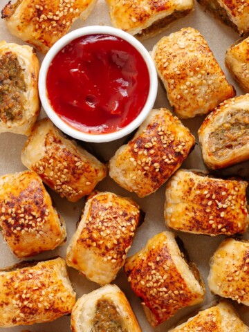 Closeup of chicken sausage rolls on a platter with small bowl of ketchup.