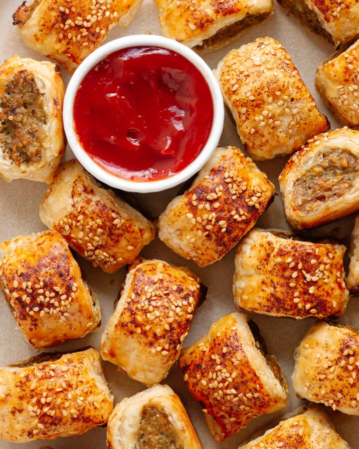 Closeup of chicken sausage rolls on a platter with small bowl of ketchup.