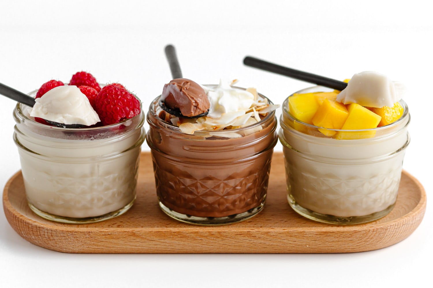 Three jars of vanilla and chocolate flavored coconut jelly with various toppings.