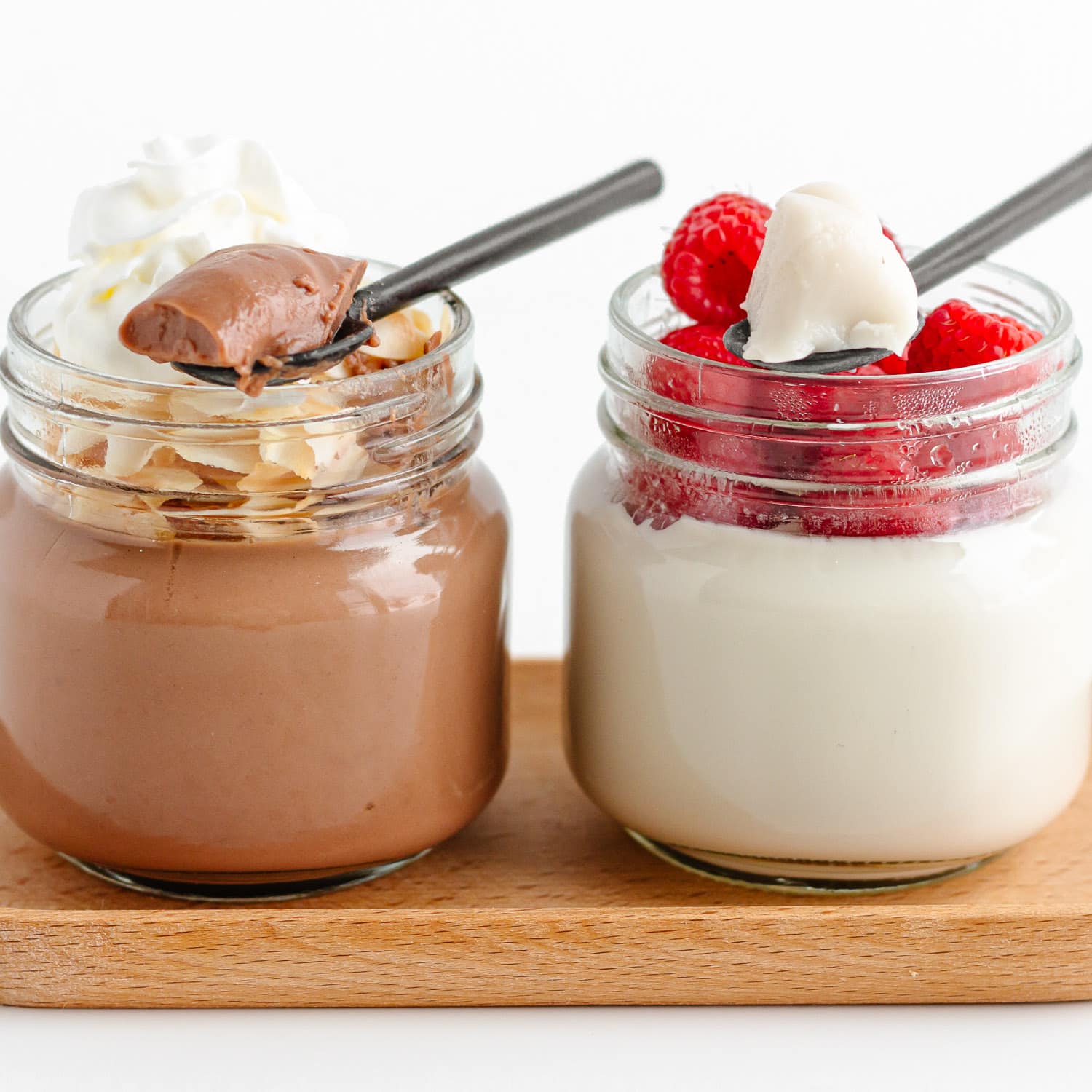 Two jars of coconut jelly with spoons scooping some out, one chocolate flavored and one vanilla.