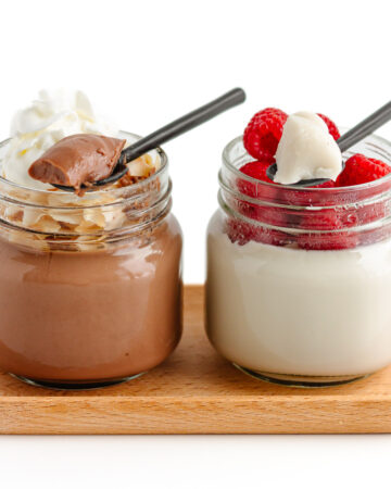 Two glass jars of coconut jelly with spoons scooping some out, one chocolate flavored and one vanilla flavored.
