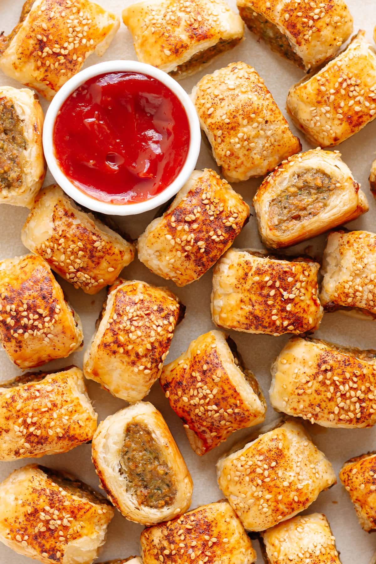 Close up of chicken sausage rolls with a small bowl of ketchup.