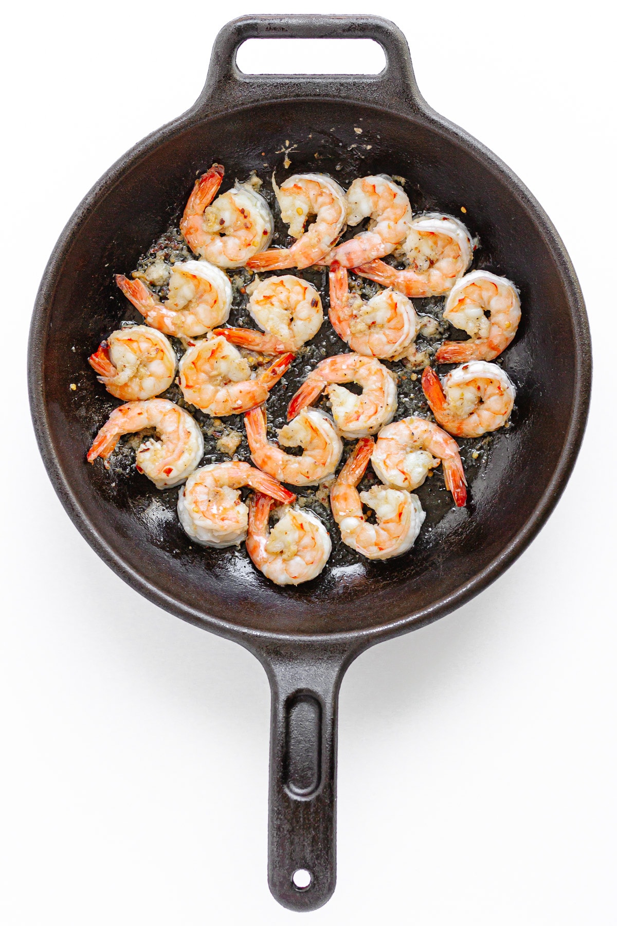 Shrimp being sauteed in a cast iron skillet.