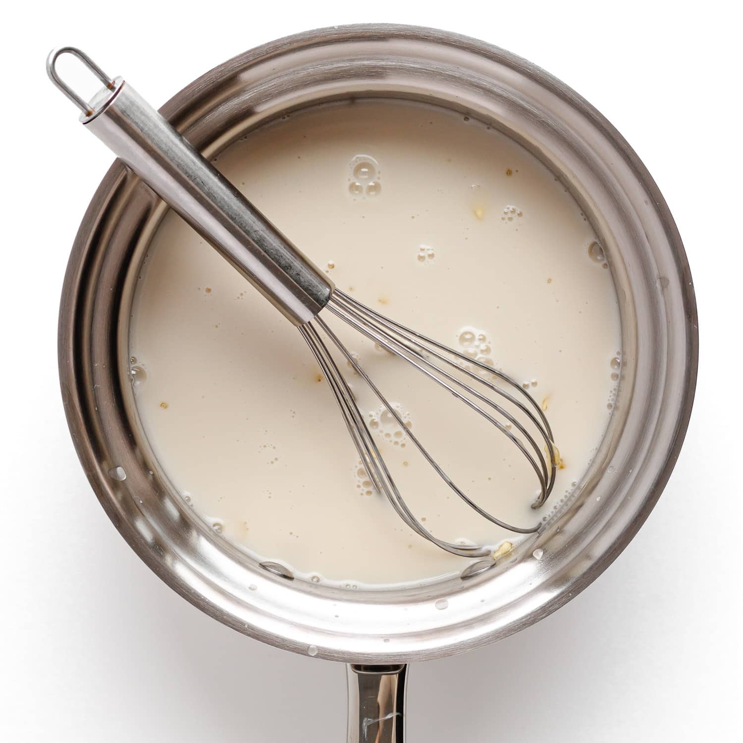 Whisking gelatin into warmed coconut milk mixture in a stainless steel saucepan.