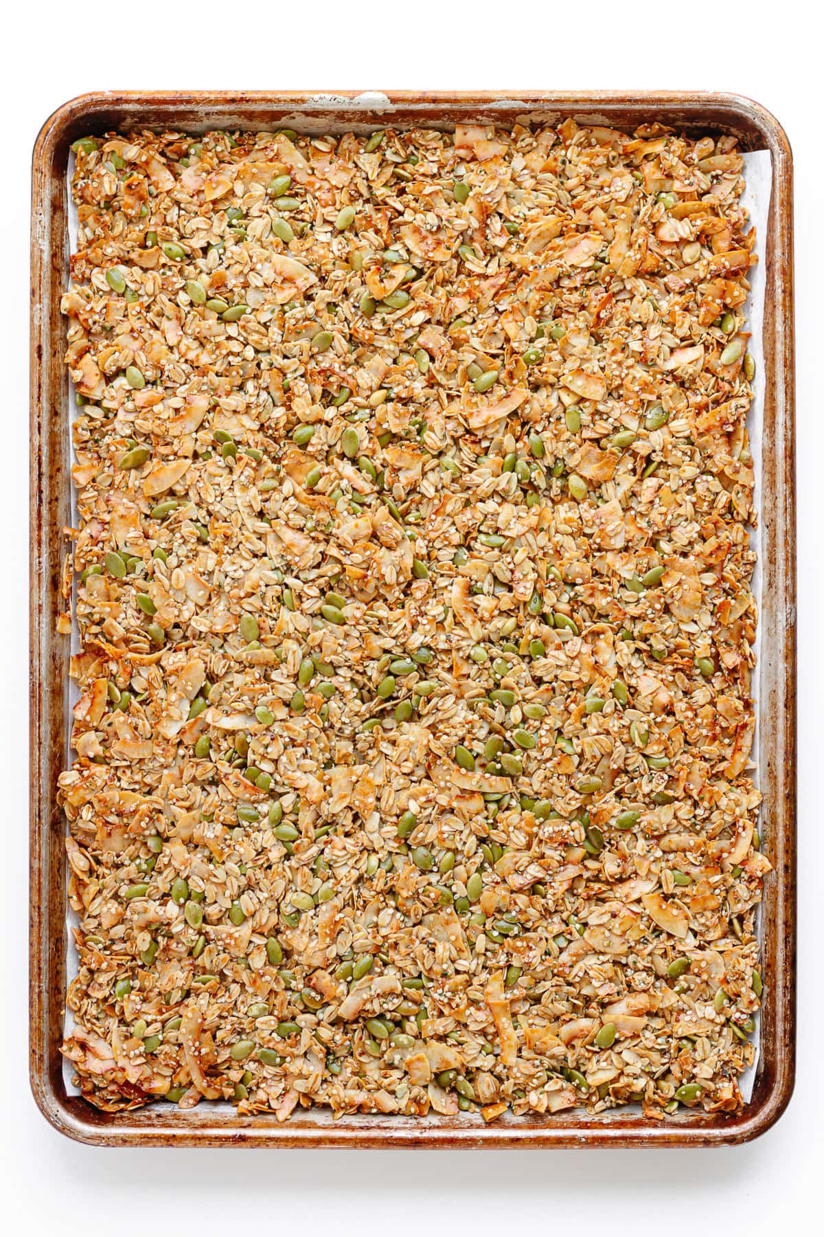 Baked vanilla coconut granola on large baking sheet before being broken up into clusters.