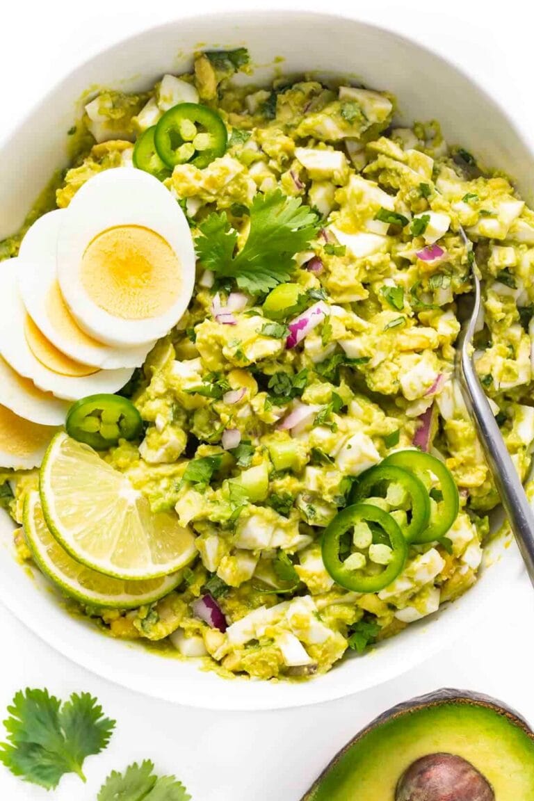 Avocado egg salad in a white bowl with spoon.