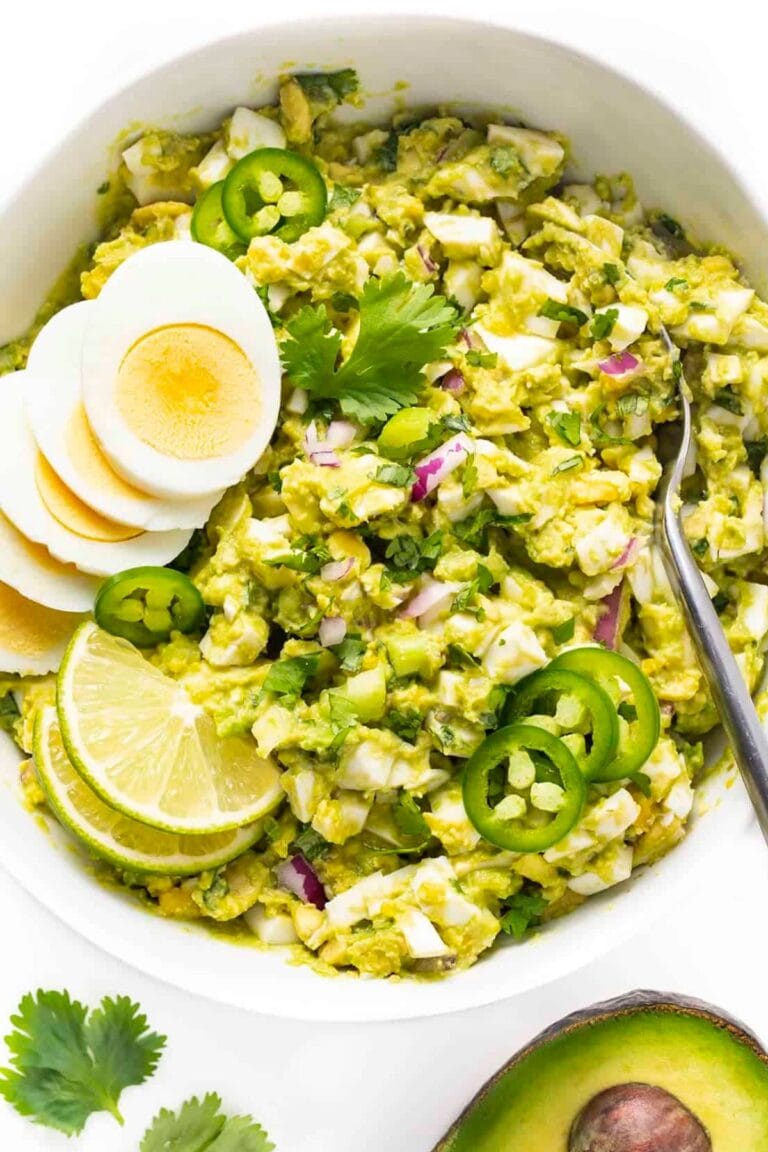 Avocado egg salad in a white bowl with spoon.