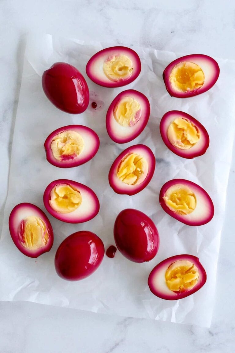 Beet pickled eggs on a sheet of parchment paper.