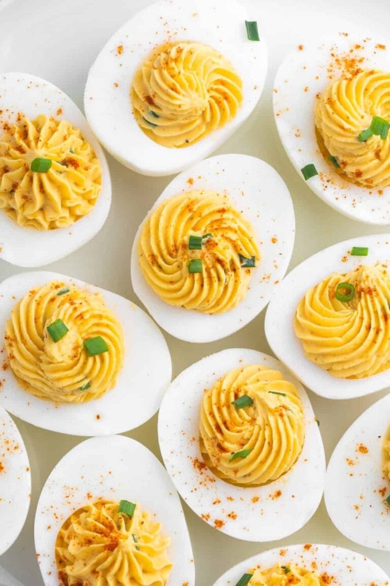 Closeup of deviled eggs garnished with chopped chives and a sprinkle of paprika.