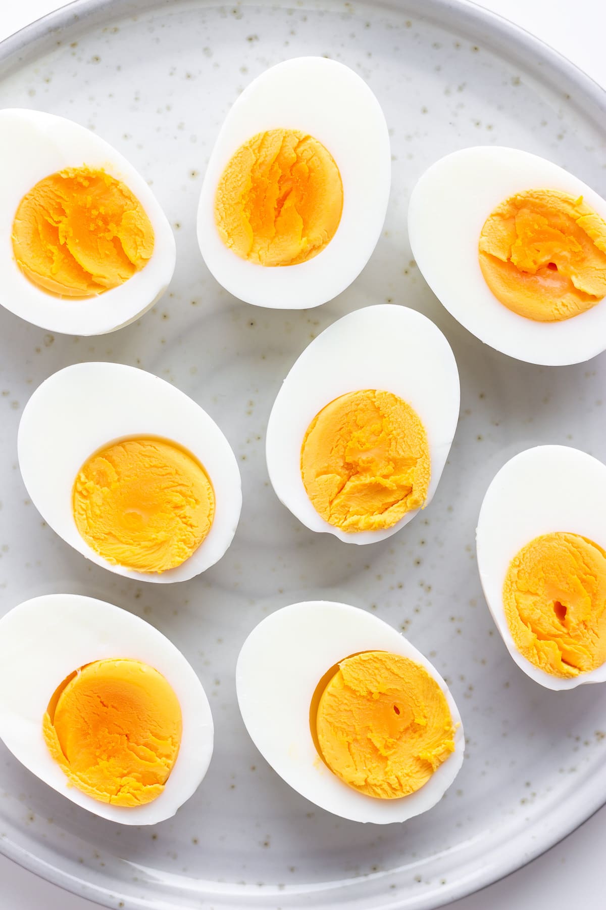 Closeup of halved hard boiled eggs arranged on a plate.