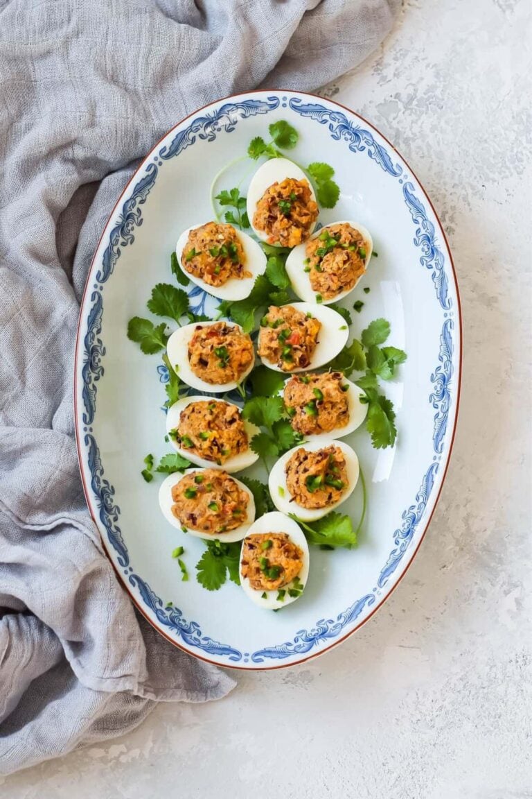 Curried deviled eggs on a serving platter with gray linen.