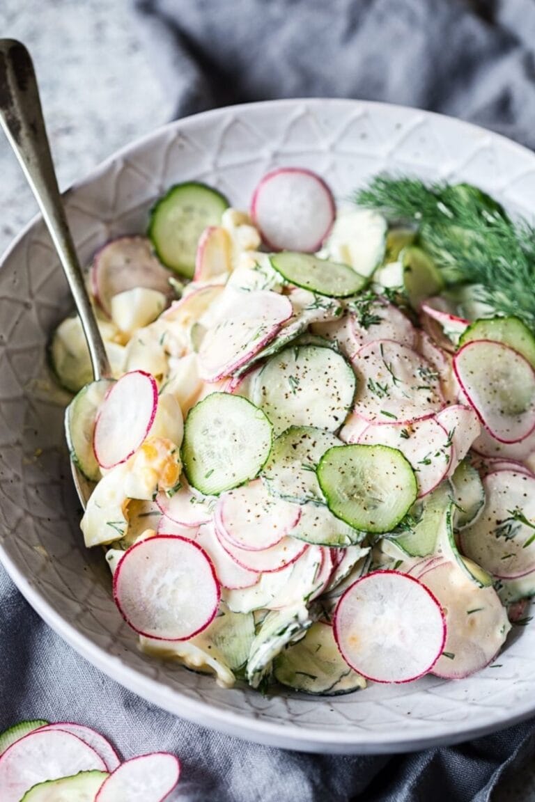 Dill cucumber radish and egg salad in a serving bowl with spoon.