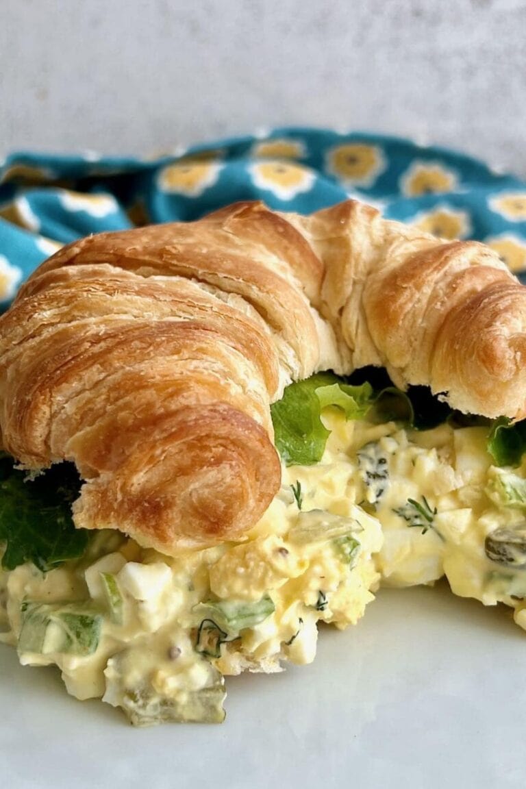 Egg salad with pickles on a croissant.