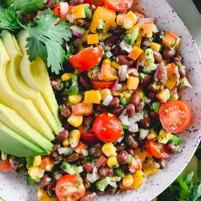 Fiesta salad in a serving bowl garnished with avocado slices and cilantro.