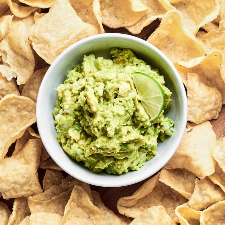 Bowl of guacamole surrounded by tortilla chips.