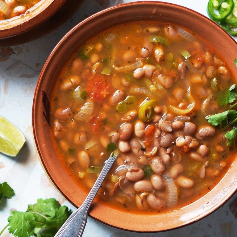 A bowl of frijoles charros with spoon.