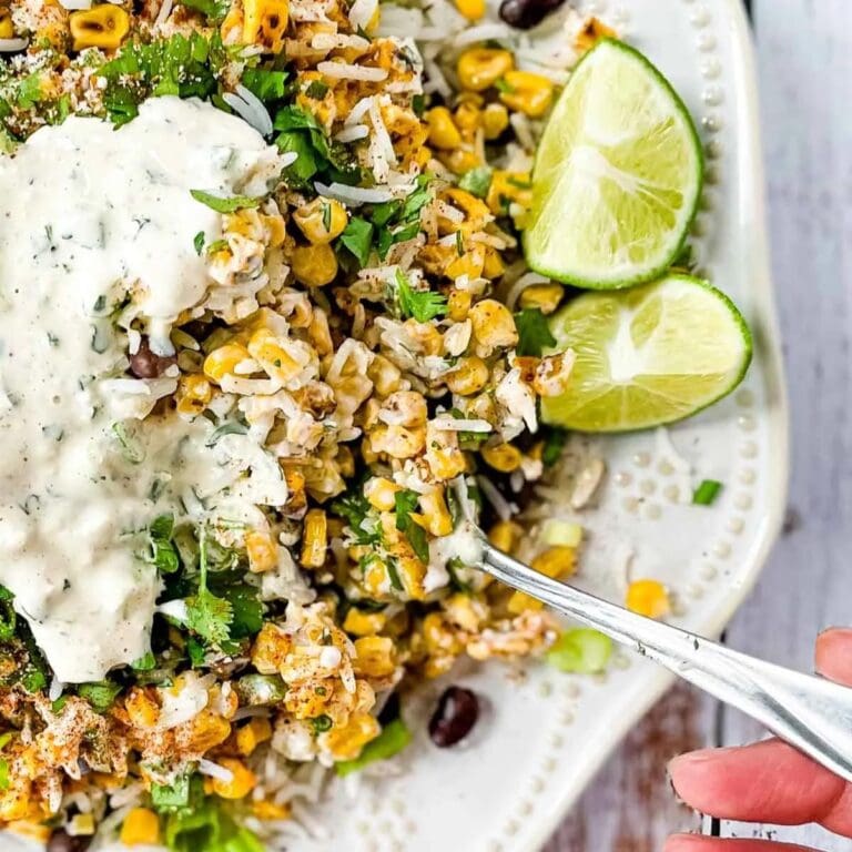 Mexican street corn rice and beans on a plate with a hand lifting out a spoonful.