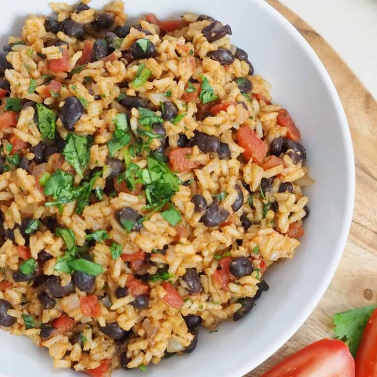 Tomato rice and beans on a serving plate garnished with chopped cilantro.