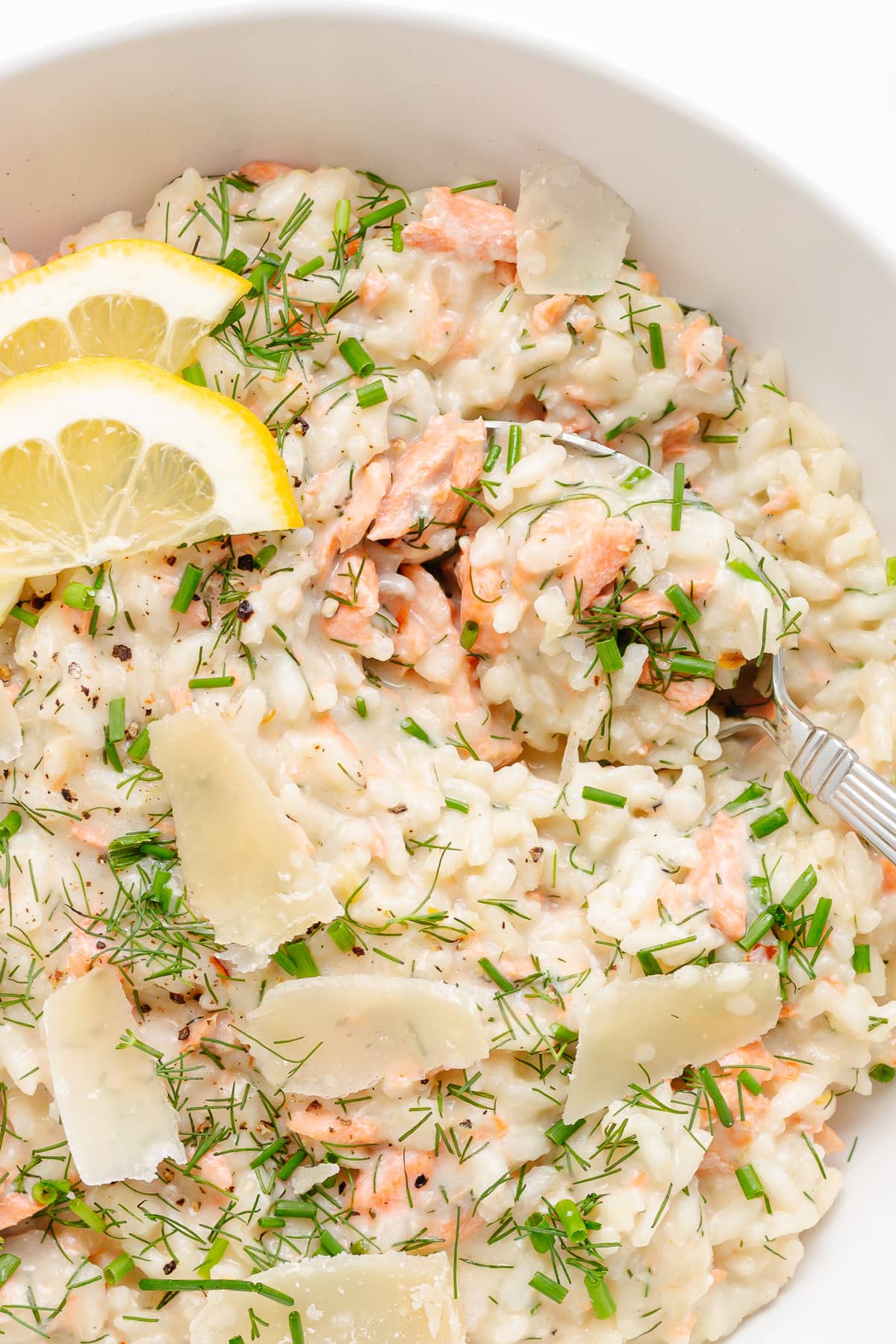 Creamy lemon salmon risotto in a white bowl with spoon.