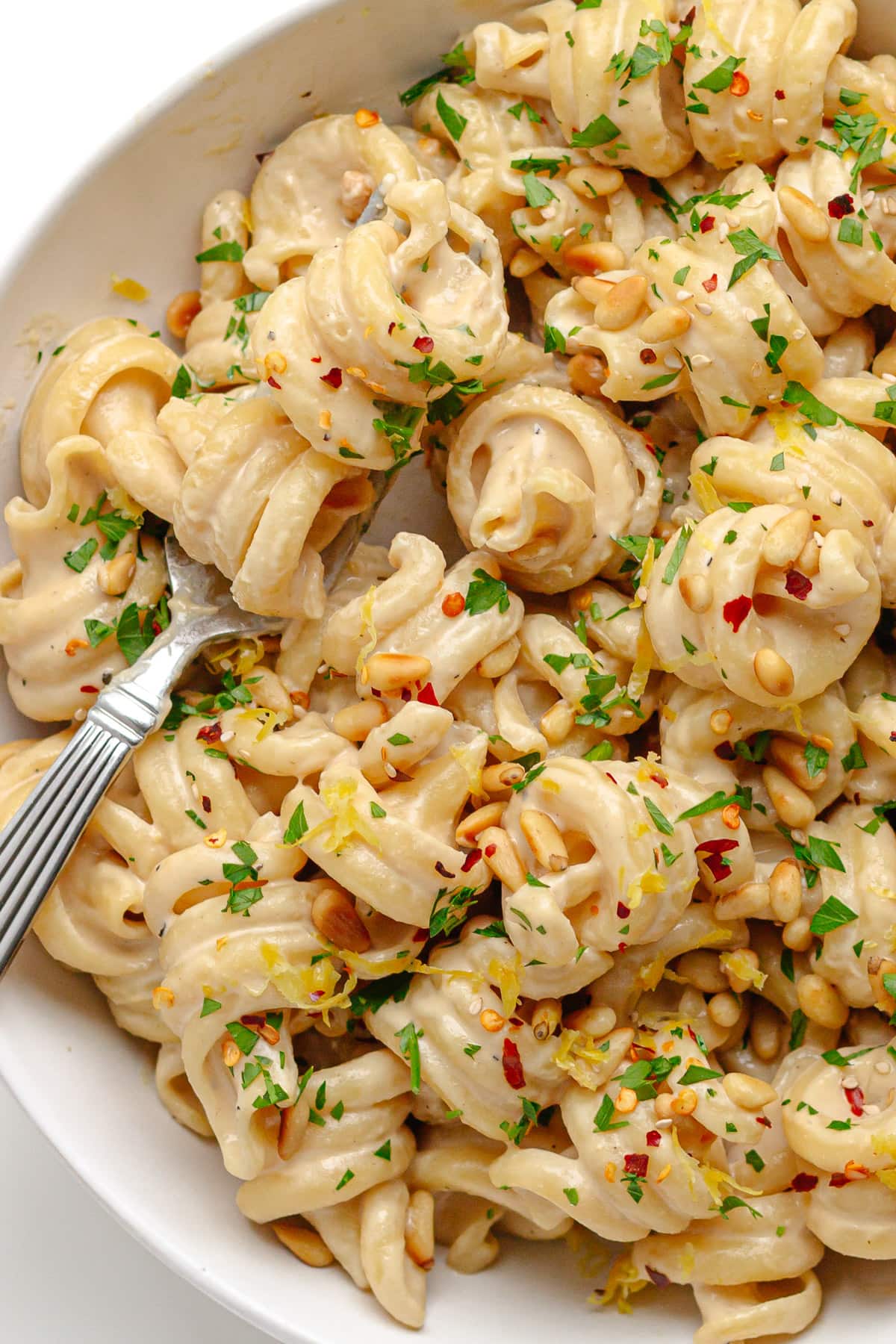 Lemon tahini pasta in a white bowl with fork.