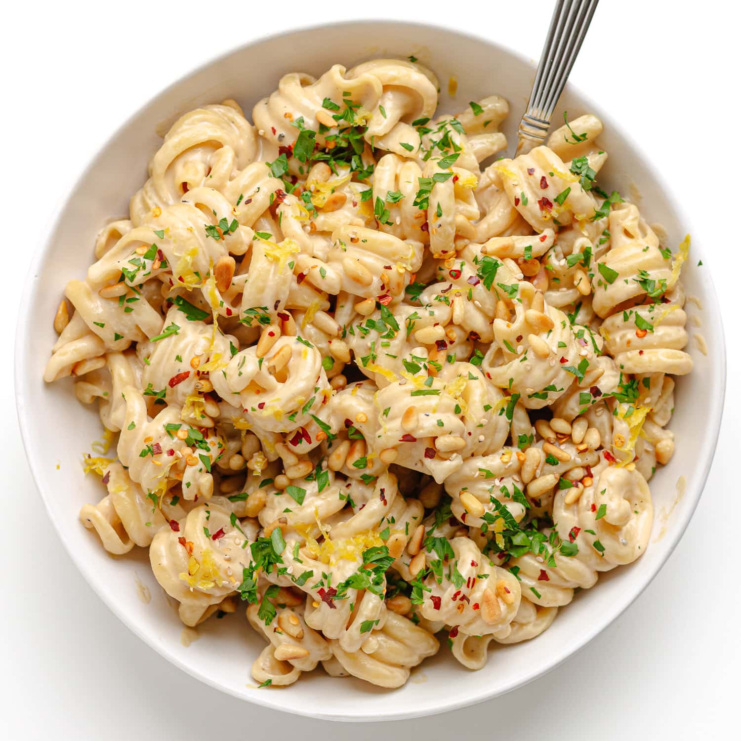 Garnished bowl of tahini pasta with fork.