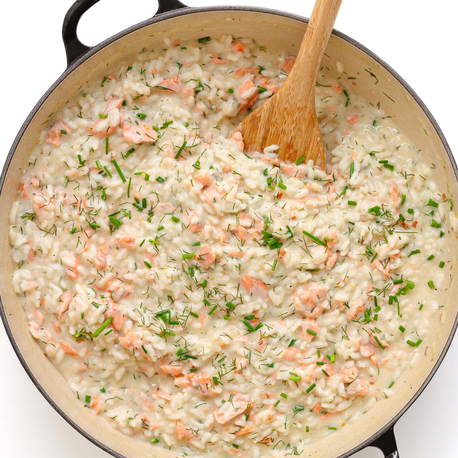 Salmon risotto in pan with wooden spoon.
