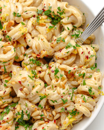 Closeup of tahini pasta in a white bowl with fork.