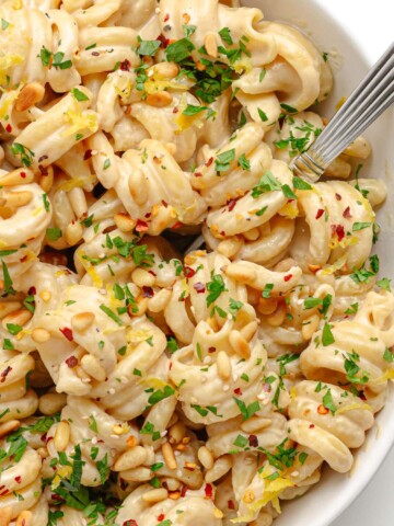 Closeup of tahini pasta in a white bowl with fork.