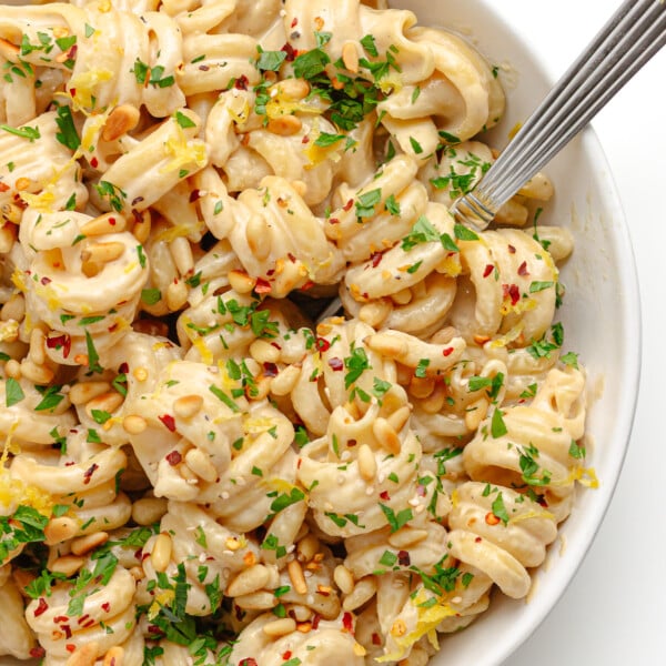 Closeup of tahini pasta in a white bowl with fork.