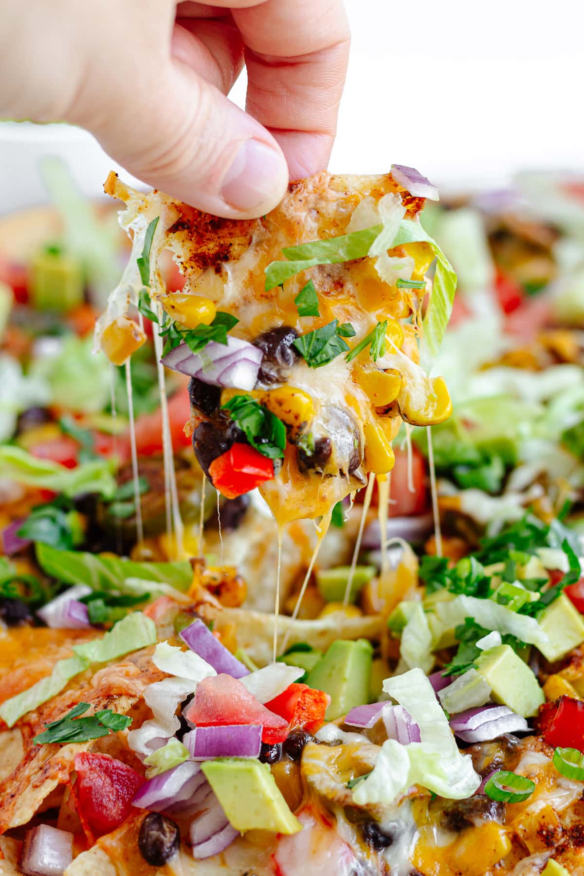 Hand picking up a loaded veggie nacho.